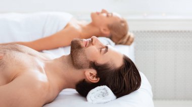 Spa Merkezi 'nde gözleri kapalı uzanan, evde masaj yaptıktan sonra dinlenen bir çift. Lüks Güzellik ve Vücut Rahatlatma Terapisi Konsepti. Panorama, Seçici Odaklanma