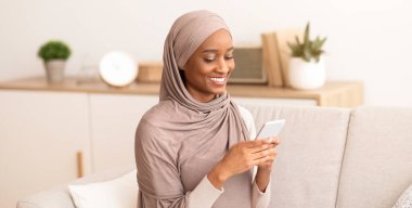 Bin yıllık Müslüman kadın tesettürde cep telefonunu iş için, iletişim için ya da evdeki rahat koltukta ders çalışmak için kullanıyor. İnternet 'e göz atan, internetten sohbet eden ya da cep telefonundan e-postaları kontrol eden neşeli bir Arap kadın.