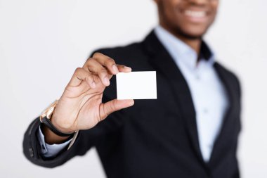 Kartvizit Model 'i. Gülümseyen siyah işadamı müşteriler ve iş ortakları için boş kart tutuyor. Boş beyaz kart, gri stüdyo geçmişi, yakın plan, kopyalama alanı üzerine seçici odaklanıyor.