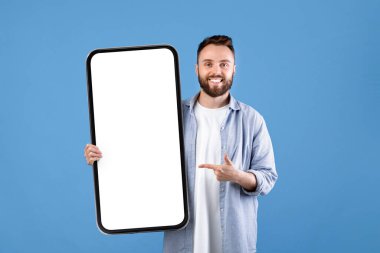 Reklam panosu reklamı. Gülümseyen genç adamın portresi boş beyaz posteri gösteriyor. Tasarımın için yer var. Mutlu milenyum insanları boş pankart şablonu sergiliyor