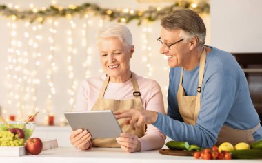 Mutlu son sınıf aşçıları dijital tablet kullanarak evde mutfakta yemek hazırlarken Noel tarifi arıyor. Yemek Başvurusu, Aile Tatil Konsepti. Boş Boşluk