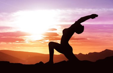 Güneş doğarken pratik yoga kadın silüeti. Selamlamak için güneş kavramı