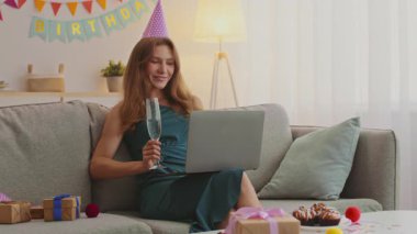 Kızıl saçlı genç bir kadın evde doğum gününü kutluyor. Bir parti şapkası takıyor ve internete bağlanırken bir bardak soda tutuyor. Etrafını hediyeler ve ziyafetler sarmış..