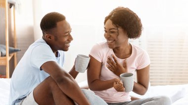 Genç, mutlu, Afro-Amerikan aile babası kadın ve erkek pijamalarıyla hafta sonunun tadını çıkarıyorlar. Evde birlikte oturup çay ya da kahve içip sohbet ediyorlar. Yatak odasının içi boş.