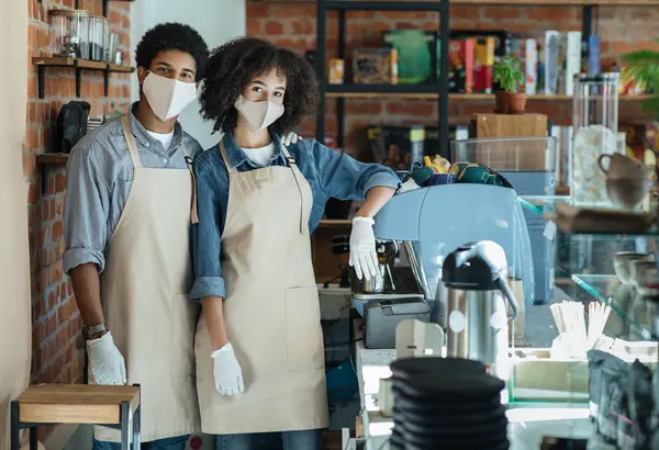 Kilitlenme, karantina, koronavirüs ve küçük işletmeler normale döndü. Afrika kökenli Amerikalı erkek ve kadın önlüklü, beyaz eldivenli ve koruyucu maskeli kahve dükkânı sahipleri modern iç mekanda