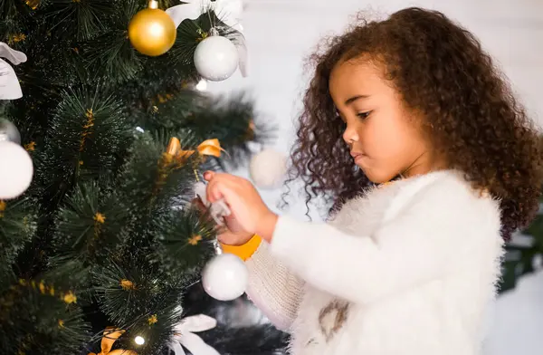 Kış tatili Odaklanmış Afrikalı küçük kız evde Noel ağacı süslüyordu, boş bir yer.
