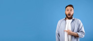 İnanılmaz bir haber. Genç sakallı adam şok içinde ağzını açıyor. Mavi stüdyo arka planındaki boşluğu işaret ediyor. Panorama. Afallamış milenyum adamı indirim ya da indirim teklif ediyor.