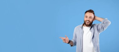 Boş uzayı gösteren mutlu genç adam mavi stüdyo arka planında büyük bir satış yaptığı için şansına inanamıyor. Fotokopi alanı olan pankart tasarımı. Yakışıklı sakallı adam ürününü tanıtıyor.