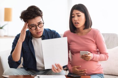 Aile Ekonomik Krizi Mücadelesi. Faturalara bakan bunalımlı Japon çift evdeki koltukta oturan masrafları ödeyemiyor. Eşlerin mali sorunları var, Coronacrisis 'ten muzdarip.
