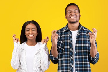 Bir dilek tut, gerçekten bir rüyanın gerçekleşmesini iste. Heyecanlı binlerce yıllık Afro-Amerikan öğrencileri elleri çapraz ve kapalı, sarı arka planda izole edilmiş, boş uzay boşluğu olan kadın ve erkekler.