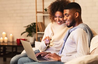 Sevgili Afro çift dizüstü bilgisayarda film seçiyor, sıcak kış akşamında birlikte dinleniyorlar, boş yer var.