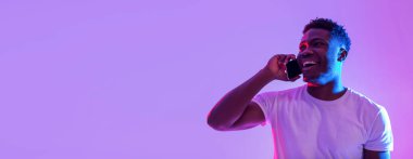 Neon ışıkta akıllı telefondan konuşan mutlu, genç siyahi bir adam, boş alanlı pankart tasarımı. Neşeli Afrikalı Amerikalı adam telefon ediyor, sohbet ediyor, iletişimin tadını çıkarıyor.
