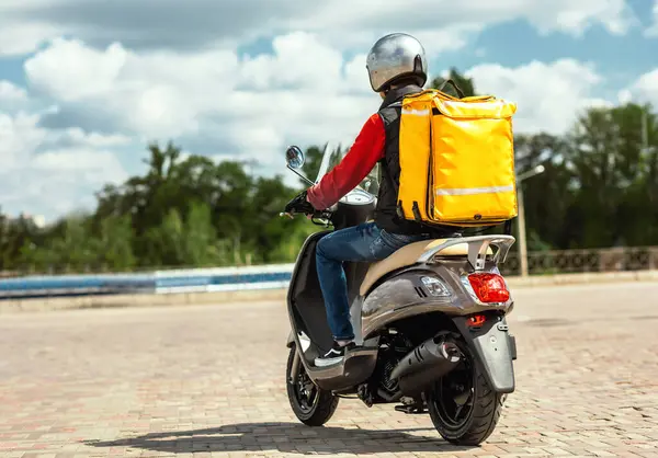 Yemek Teslimat Servisi. Sarı Sırt çantalı Kurye Scooter 'a biniyor ve şehir dışındaki restoranları dağıtıyor. Geri Görünüm, Boş Boşluk