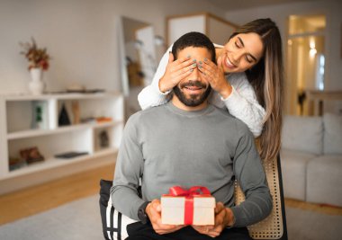 Mutlu bin yıllık Avrupalı kadın Arap erkeğine gözlerini kapar, hediyeyle kutlar, tatilini odada kutlar. Doğum günü, yıldönümü ve sevgililer günü için sürpriz, aşk, evdeki ilişkiler