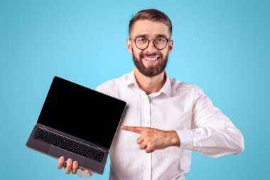Mavi stüdyo arka planında web sitesi tasarımı için dizüstü bilgisayarı gösteren mutlu milenyum işadamları. Gülümseyen genç erkek girişimci taşınabilir bilgisayarlı, metin için alan