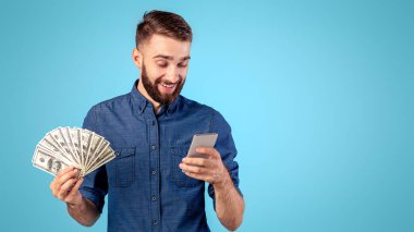 Paralı ve cep telefonlu neşeli genç adam piyango ya da kumarhane bahsi kazanan mavi stüdyo geçmişi. Dolar banknotları ve akıllı telefonları olan zengin bir adam online bankacılık hizmetini kullanıyor, kredi alıyor.