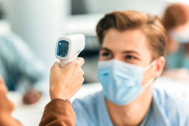 Vücut ısısını kontrol et ve kontrol et. Öğretmen 'in elini tutup, temassız olarak kızıl ötesi kameraya bakarken, temassız silahla ateşi ölçerken, öğrencinin alnını tararken...