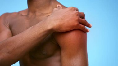 Yaralı omzunu renkli bir geçmişe karşı sunan genç bir Afrikalı Amerikalı. Spor faaliyetleri sırasında yaralanmalar