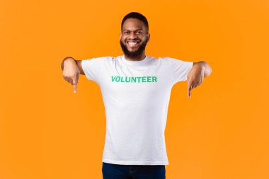 Afrikalı Gönüllü Adam, parmaklarını göstererek kameraya gülümsüyor. Stüdyoda duran bir şeyin reklamını yapan aktivist. Gönüllü Reklam. Şuraya bak Kavram