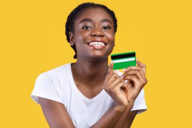 Neşeli Afrikalı Kadın Kamera Öneren Banka Pozisyonuna Kredi Kartı Gösteriyor Sarı Arkaplanda Duruyor. Stüdyo çekimi. Siyahi Kadın Bankacılık Ödeme Servisi Kavramı