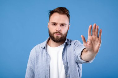 Uzak dur, mesafeni koru. Mavi stüdyo arka planında kameradan kameraya DUR hareketi gösteren hoşnutsuz genç adam. Bin yıllık ciddi bir adam reddedildiğini ya da yasaklandığını söylüyor.