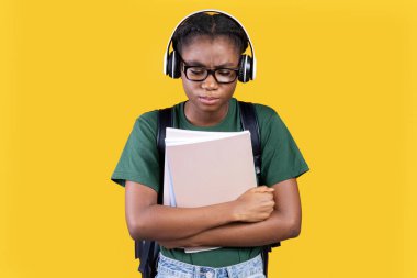 Sarı Stüdyo Arkaplanının Üzerinde Duran Mutsuz Mağdur Afrikalı Kız Fotokopi Kitapları Tutuyor. Düşük Öz Saygı, Gençler Depresyonu, Gençler Antisosyal Davranış Konsepti