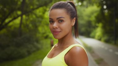 Milenyum kadını, güneşli bir günde parkta koşmaktan zevk alıyor. Odaklanmış ve kararlı ifadesi, spor yapmaya ve sağlıklı bir yaşam tarzına olan bağlılığını yansıtıyor..