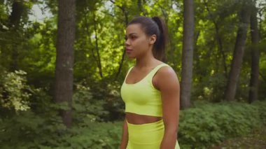 Genç bir Afrikalı Amerikalı kadın yemyeşil bir parkın içinde koşuyor. Parlak atletizm kıyafetleri içinde, zindelik ve sağlığa olan bağlılığını somutlaştırıyor..