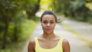 Genç bir Afrikalı Amerikalı kadın sakin bir park yolunda koşuyor. Enerjik ve sağlıklı bir yaşam tarzını somutlaştırıyor. Koşarken etrafındaki temiz havanın ve doğanın tadını çıkarıyor..