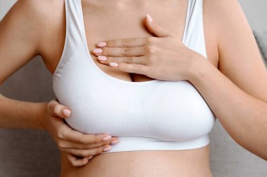 Breast Diseases During Pregnancy. Unrecognizable Pregnant Lady In Top Bra Massaging Chest Area While Sitting On Couch At Home, Expectant Lady Suffering Body Changes While Expecting Baby, Cropped