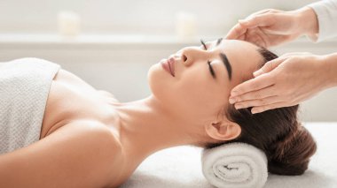 Sakin, genç Asyalı bir bayan spa salonunda yüz masajından hoşlanıyor. Masaj masasında uzanan Koreli güzel bir kadın. Profesyonel masörle sağlık tedavisinden hoşlanıyor.