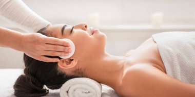 Profesyonel kozmetik uzmanı, kaplıcadaki yüz bakımı sırasında Asya 'lı genç bir kadının derisini temizliyor, Güzellik salonunda dinlenen Koreli bir kadın, Masaj masasında uzanan, yan görüş