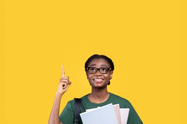 Yukarı bak. Sarı Stüdyo Geçmişi ile ilgili kitap tutan harika bir fikri olan mutlu Afrikalı Öğrenci Kadın. İlham ve Eureka Anı Kavramı. Kare Vuruş