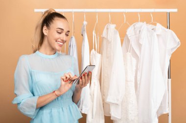 Satış ve İndirim Sezonu. Gülümseyen genç bir kadının portresi cep telefonunu tutuyor, sohbet ediyor ya da internetten alışveriş yapıyor stüdyonun korkuluklarının yanında dikiliyor.