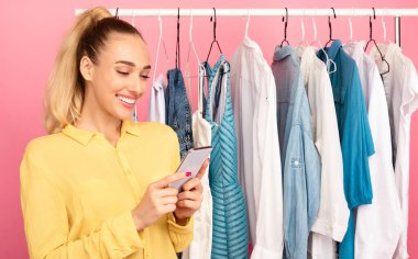 Gülümseyen moda blogcusunun portresi akıllı telefonunu tutuyor ve kullanıyor, SMS yolluyor, sosyal medyayı kontrol ediyor, yazı yazıyor ya da internetten alışveriş yapıyor.