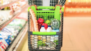 Marketten yiyecek satın alan, sebze, süt ve ekmekle dolu bir tramvayı elinde tutan alışveriş arabası olan siyah adam. Müşteri Market Konsepti 'nden alışveriş yapar. Kırpılmış, Seçici Odaklanma, Boşluğu Kopyala