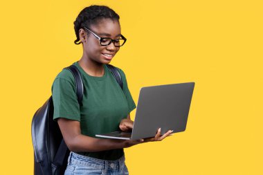 Sarı Stüdyo Arkaplanının Üzerinde Dizüstü bilgisayar kullanan neşeli siyahi kadın. Uzaktan Eğitim, E-Öğrenme ve Online Çalışma Konsepti. Boşluğu Kopyalayan Panorama