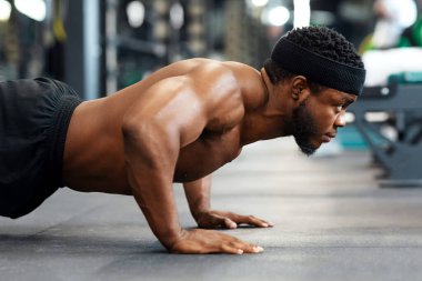 Şınav, şınav. Kaslı Afro-Amerikan tişörtsüz adam kaslarını geliştiriyor, modern spor salonunda siyah adam antrenmanı yapıyor, şınav çekiyor ve fotokopi odasına bakıyor, panorama...