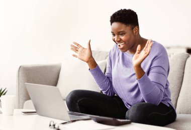 Video çağrısı. Neşeli Afrikalı Afrikalı Amerikalı kadın evde dizüstü bilgisayar kullanarak buluşuyor, Arkadaşlarıyla internette web konferansı yapıyor, Çevrimiçi iletişimin tadını çıkarıyor,