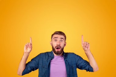 İnanılmaz bir tanıtım. Turuncu stüdyo arka planındaki boşluğu işaret eden hipster adam şok oldu. Bin yıllık bir adamın ürününüzü tanıtması sürpriz oldu. Büyük satış ya da indirim ilan etti.