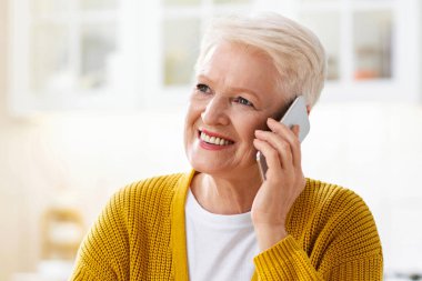 Sağlıklı yemek yiyen, cep telefonuyla konuşan mutlu, çekici, yaşlı bir kadın. Gülümseyen yaşlı kadın yemek saatinde akıllı telefondan konuşuyor, fotokopi odasına bakıyor.