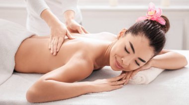Spa Salonunda sırt masajından hoşlanan genç Asyalı kadın profesyonel masörden rahatlatıcı bir muamele görüyor, Masada uzanan Koreli Kadın Kapalı Gözler, Yakın Görünüm, Yakın Çekim