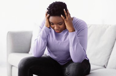 Yorgun, genç bir kadının portresi. Stres, acı ve baskıdan muzdarip. Sorunlar yaşıyor, iş sorunları yaşıyor, evdeki kanepede oturuyor.