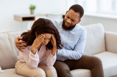 Sorunlar ve manevi destek. Afro-Amerikan erkeğini seven, ağlayan stresli kadınını rahatlatan, kavga üstüne özür dileyen, kız arkadaşının omzuna sarılan, kanepede oturan...