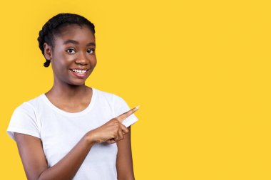 Şuraya bak. Gülümseyen Afrikalı Kadın Boş Alan 'ı Parmakla Gösteriyor Sarı Stüdyo Arkaplanındaki Mesajını Yazıyor. Şuna bir bak. Reklam afişi. Panorama