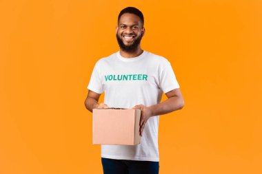Afrikalı Amerikalı Gönüllü Adam Bağış Kutusu Sarı Stüdyo Arkaplanda Kameraya Gülümsüyor. Gönüllü İş ve Yardım Teslimatı