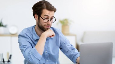 Gözlüklü iş adamının bilgisayara bakması ve modern ofisteki masada oturması sürpriz oldu. İnternet Bağlantısı Konsepti. Seçici Odaklanma