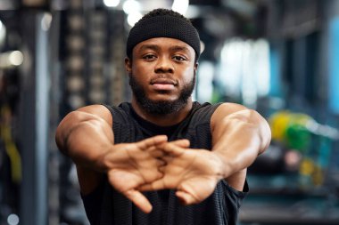 Konsepti ısıtıyorum. Spor yapmadan önce ellerini uzatan Afrikalı Amerikalı sakallı bir sporcunun portresi spor salonunda vücut geliştirme eğitimi alan kaslı bir zenci.