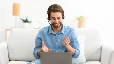 İş adamı Laptop 'ta Eğitimci İşletmeleri izlerken çevrimiçi olarak koltukta oturan kulaklığı takıyor. Uzak Bilgisayar Çalışmaları, Video Çağrısı ve İnternet İş Eğitimi Konsepti