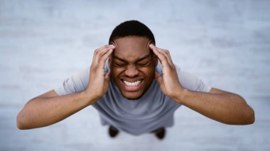 Siyahi adamın baş ağrısının baş ağrısının baş ağrısının baş ağrısının baş ağrısının baş ağrısının gri arka planda durmasının en üst görüntüsü. Erkek Sağlığı Sorunu Konsepti. Panorama, Seçici Odaklanma